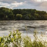 A scenic view looking over a river with green trees on the other side.