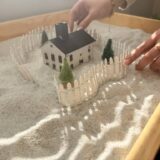 A woman with her hands above a sand tray